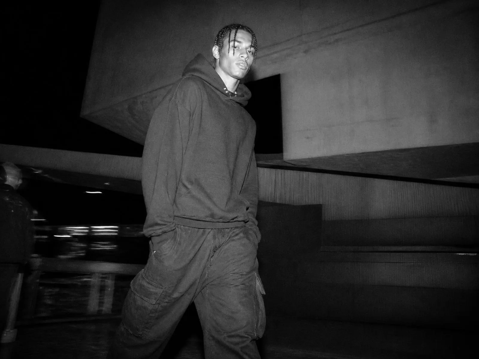 Modelo con hoodie de peso pesado en un aparcamiento de hormigón de noche